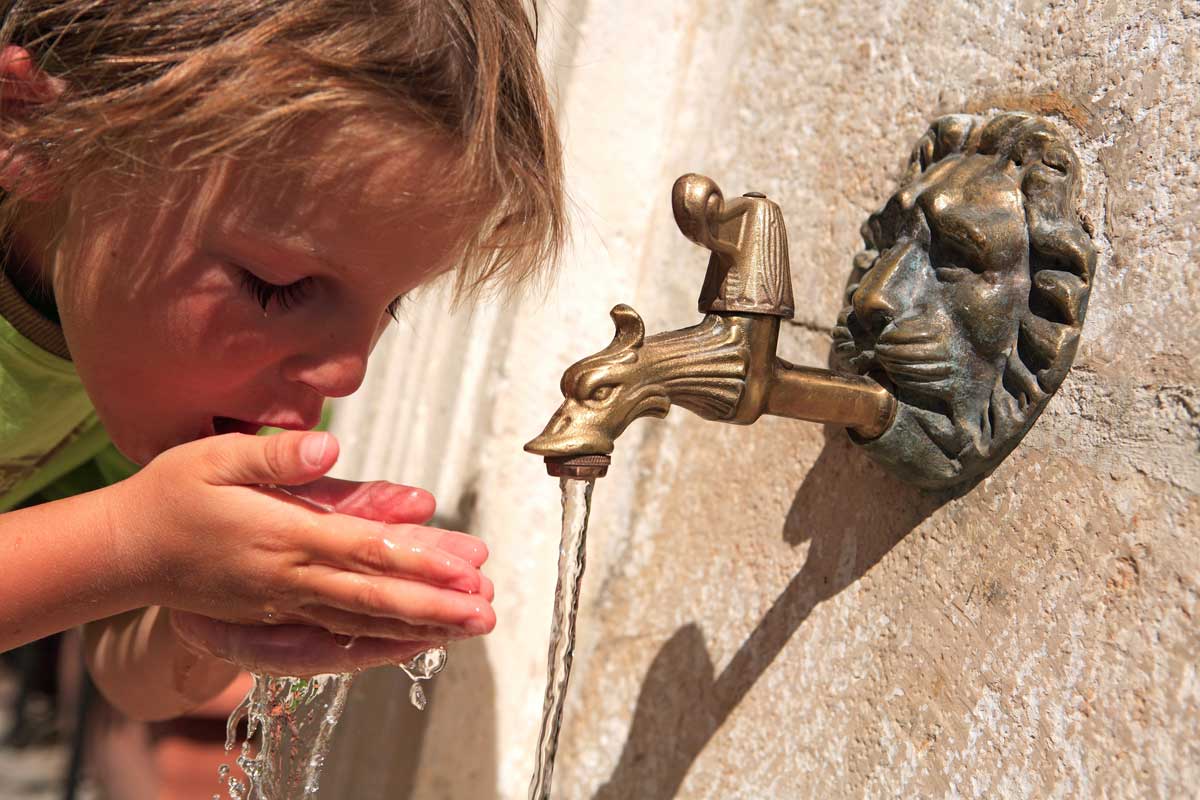 Enfant buvant l'eau d'une fontaine